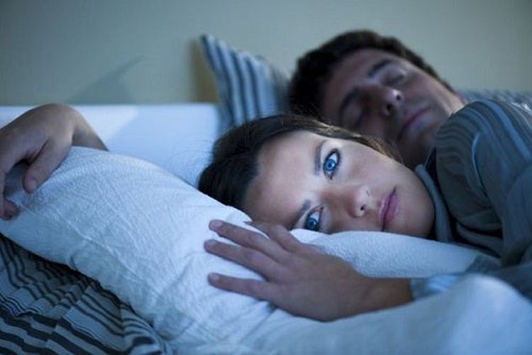 The woman in the bed cannot sleep while the man behind her sleeps