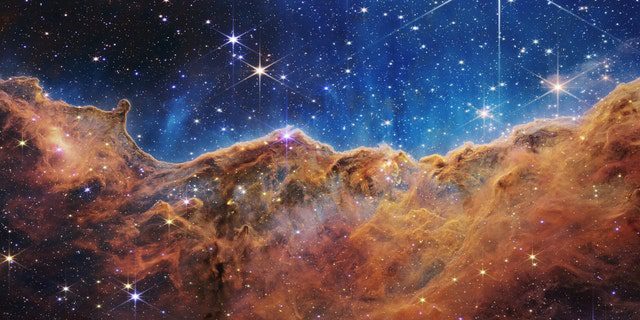 What looks a lot like the Rocky Mountains on a moonlit evening is actually the edge of the nearby young star-forming region NGC 3324 in the Carina Nebula.  Taken in infrared light from the Near Infrared Camera (NIRCam) on NASA's James Webb Space Telescope, this image reveals previously obscured regions of star birth.